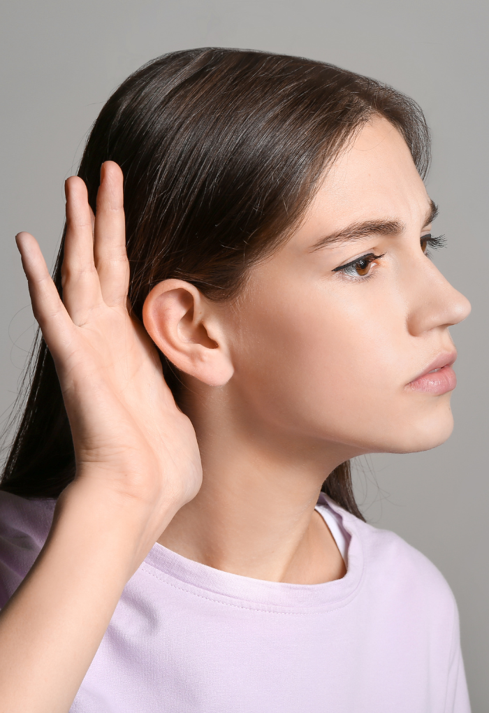 Persona colocando la mano en el oído intentando escuchar mejor como señal de posible dificultad auditiva
